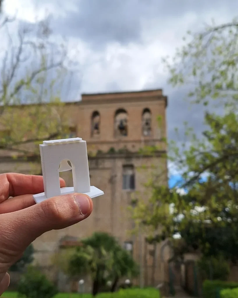 In primo piano il totem progettato dai ragazzi della classe di San Nicola la strada, ispirato ai campanili della chiesa Stan Maria degli angeli, che si intravede sullo sfondo fuori fuoco
